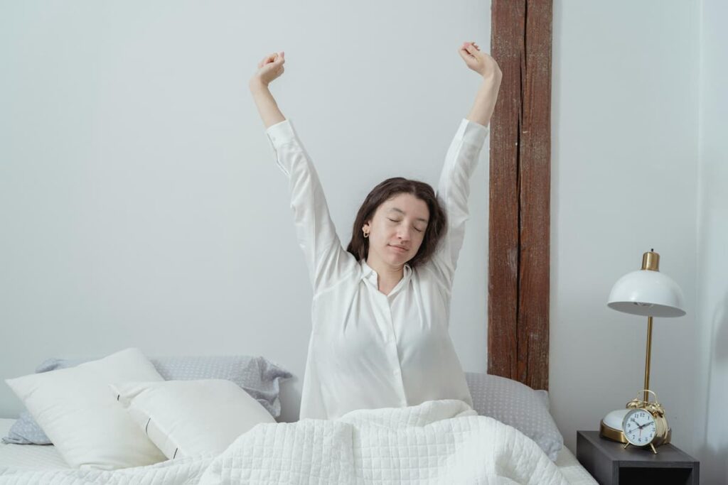A woman stretching in bed after a restful night's sleep as part of a healthy morning routine