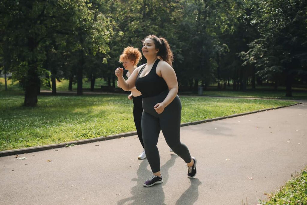 Woman running outdoors in a park, representing the experience of building healthier habits through running