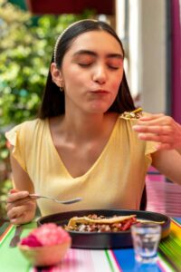 Woman mindfully enjoying a healthy meal, representing balanced eating habits and a healthier relationship with food