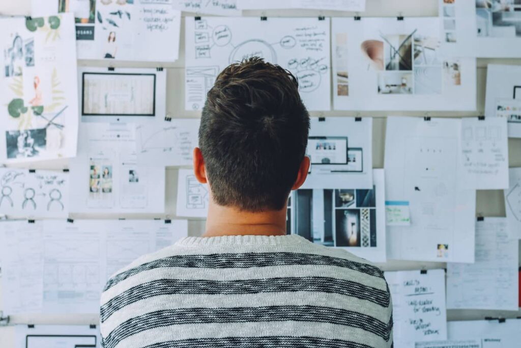 A person looking at a wall with notes and ideas while planning future goals