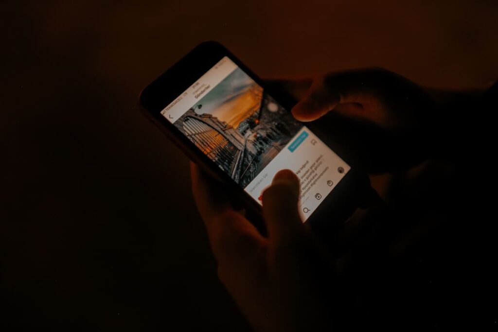 A person scrolling through social media on a phone in the dark, taking in glimpses of other people's lives
