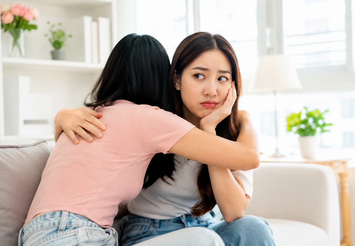 A woman looking uncomfortable while hugging a friend, showing how a close relationship can sometimes leave us feeling uneasy or emotionally drained. 